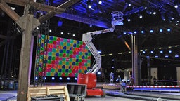 Bei den Aufbauarbeiten zum Deutschen Radiopreis steht ein Monteur auf einer Hebebühne. © NDR Foto: Janine Kühl